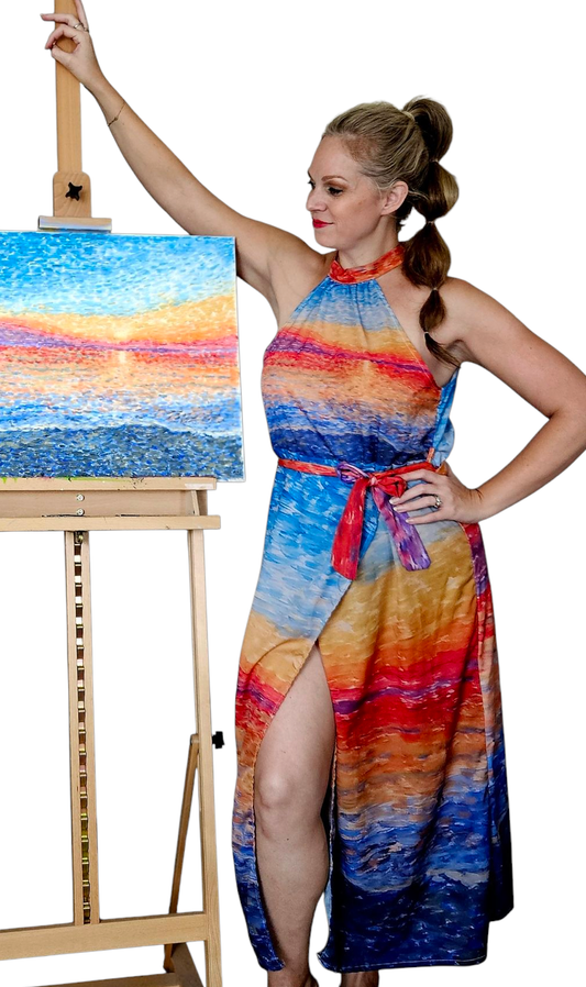 A woman in a colorful halter vacation resort dress. It is high neck, tie waist, and mid length.