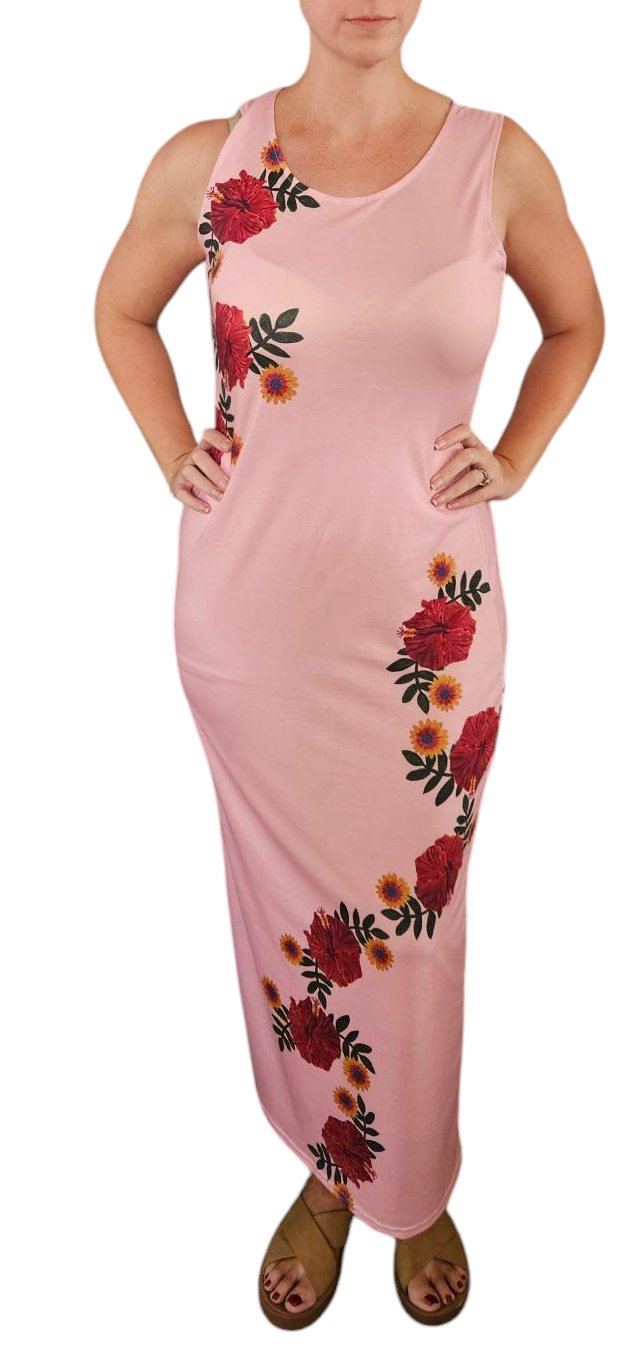 A woman in a sleeveless T shirt dress, it is midi length. The dress is light pink with hibiscus flowers wrapping around the top and side. This is a casual t shirt dress